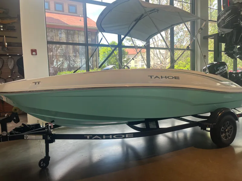 Slide: The Image of 2025 Tahoe T16 boat with canopy on display indoors, featuring sleek design and light blue hull. - 0