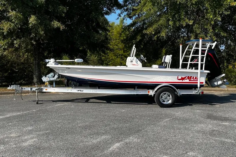 Slide: The Image of 2025 Mako Pro Skiff 18 Patriot Edition boat on trailer, parked outdoors. - 2