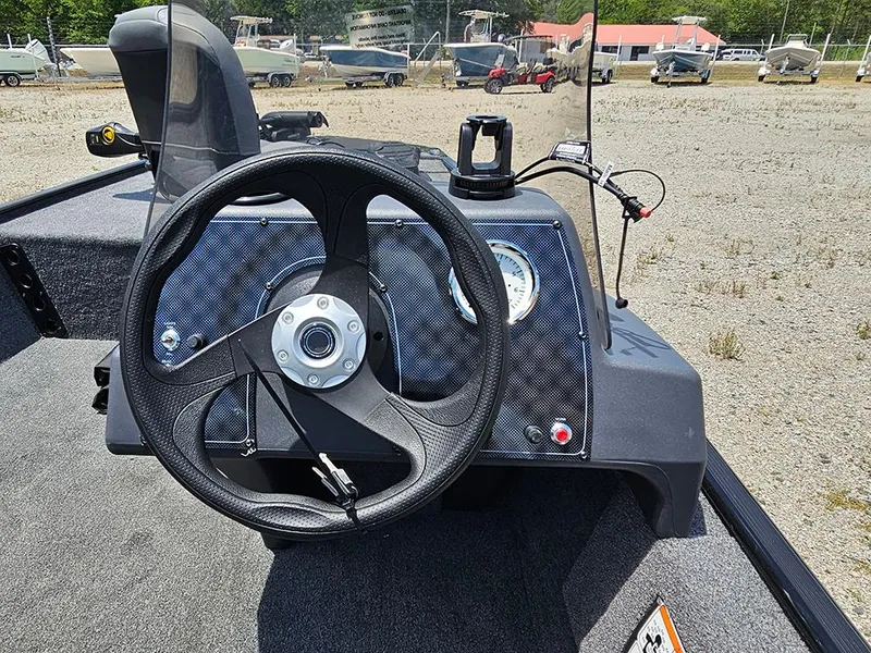 Slide: The Image of 2025 Tracker Bass Tracker Classic XL steering console with carbon fiber finish in a boatyard. - 14