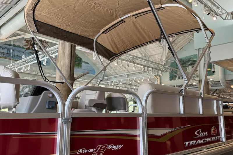 Slide: The Image of 2025 Sun Tracker Bass Buggy 18 DLX pontoon boat with canopy, displayed indoors. - 2