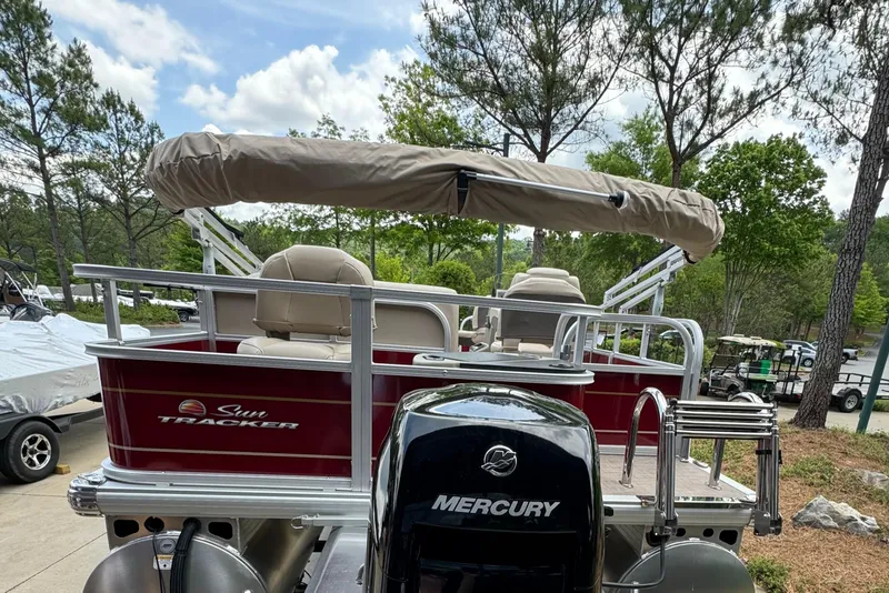Slide: The Image of 2025 Sun Tracker Bass Buggy 18 DLX pontoon boat with Mercury engine, parked outdoors. - 3