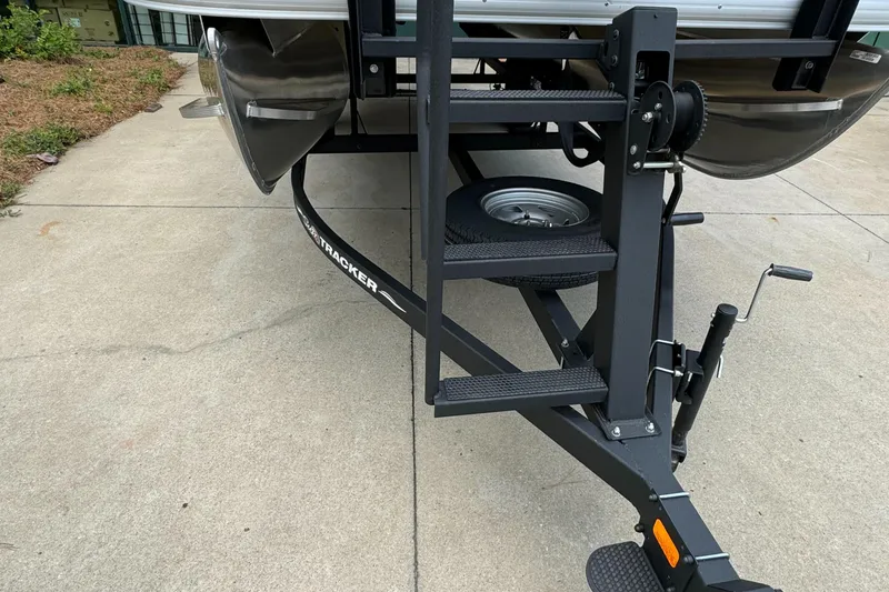 Slide: The Image of 2025 Sun Tracker Bass Buggy 18 DLX trailer with steps on concrete driveway. - 4