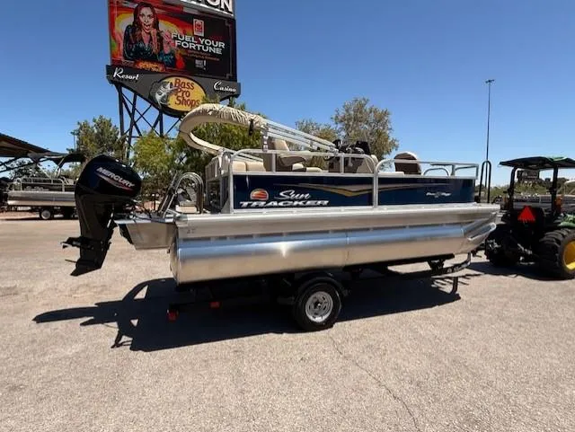 Slide: The Image of 2025 Sun Tracker Bass Buggy 16 XL Select pontoon boat on trailer, outdoor setting. - 3