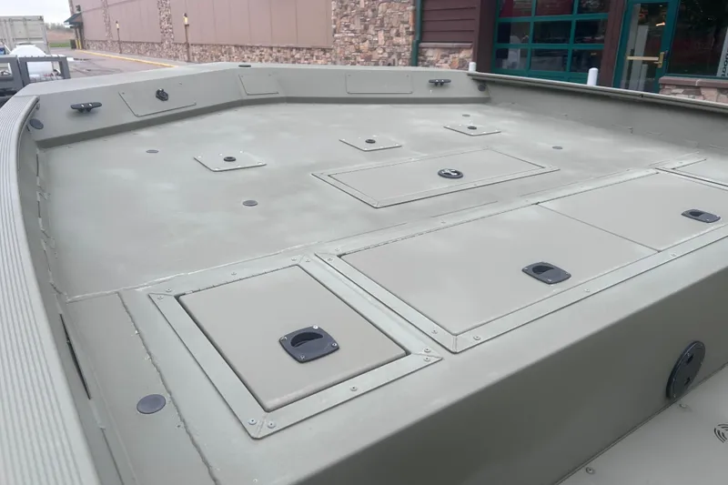 Slide: The Image of 2024 Tracker Grizzly 2072 CC boat deck with storage compartments, displayed outdoors. - 17