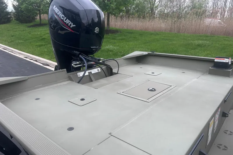 Slide: The Image of 2024 Tracker Grizzly 2072 CC boat with Mercury outboard motor, parked on grass. - 7