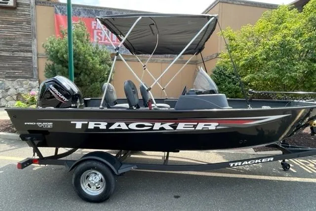 The Image of 2025 Tracker Pro Guide V-16 SC boat with canopy on trailer, outdoor setting. - 0