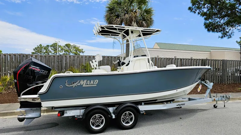 The Image of 2024 Mako 214 CC boat on trailer, parked outdoors, with palm trees in the background. - 0