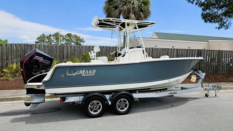 Slide: The Image of 2024 Mako 214 CC boat on trailer, parked outdoors, with blue and white hull. - 13