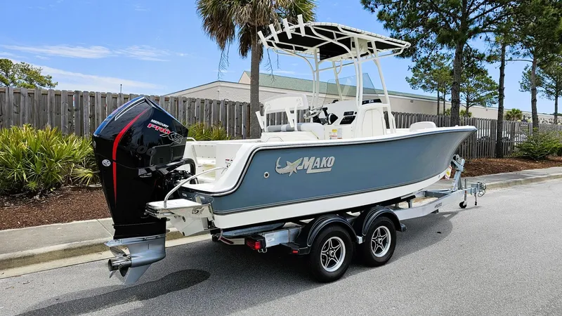 Slide: The Image of 2024 Mako 214 CC boat on trailer, parked on a street with trees and fence. - 4