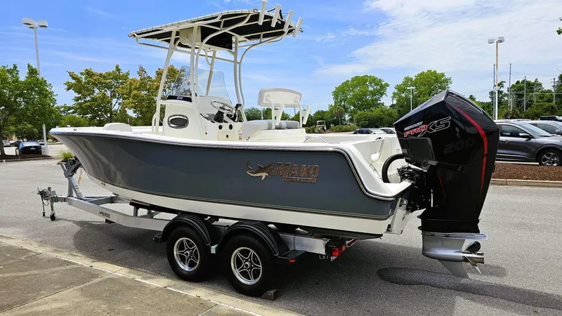 Slide: The Image of 2024 Mako 214 CC boat on trailer, parked outdoors, featuring sleek design and powerful outboard motor. - 6