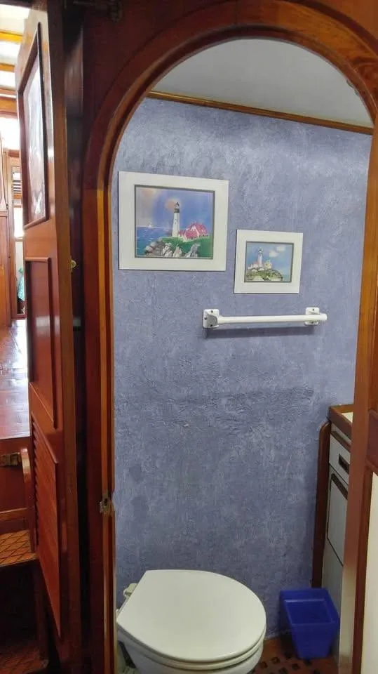 Slide: The Image of 1979 Universal Marine 41 bathroom with blue walls, framed art, and wooden door. - 12