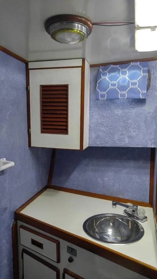 Slide: The Image of 1979 Universal Marine 41 yacht bathroom with sink, blue walls, and wooden accents. - 13