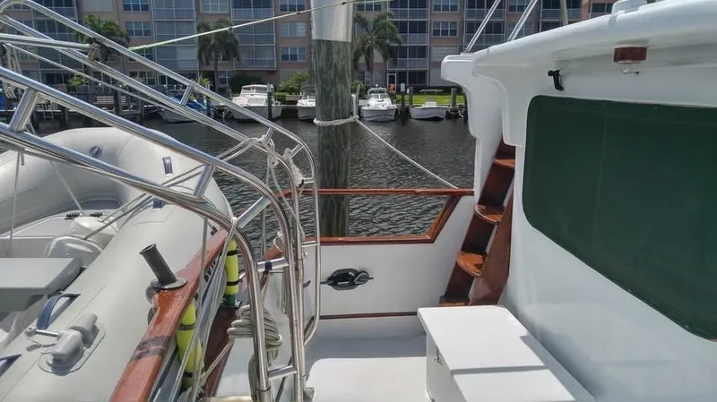 Slide: The Image of 1979 Universal Marine 41 yacht deck with marina view, featuring polished railings and wooden accents. - 4