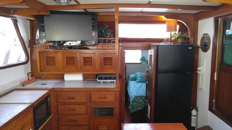 Slide: The Image of 1979 Universal Marine 41 interior with kitchen, TV, fridge, and cozy sleeping area. - 7