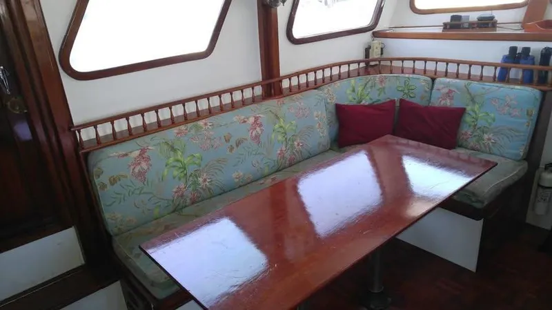 Slide: The Image of Cozy seating area on a 1979 Universal Marine 41 boat with floral cushions and wooden table. - 9