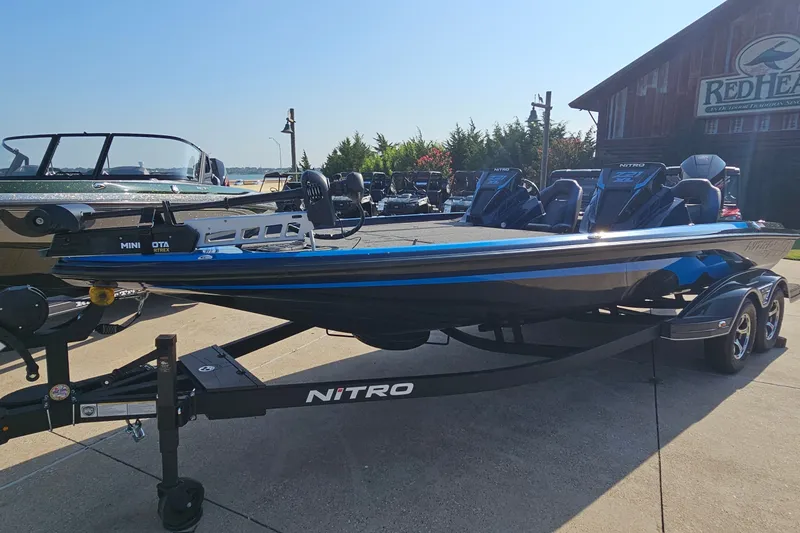 Slide: The Image of 2025 Nitro Z21 XL boat on trailer, parked outdoors near a rustic building. - 1