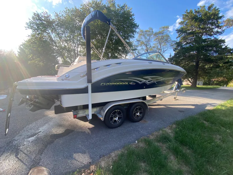Slide: The Image of 2014 Chaparral 224 Sunesta boat on trailer, parked outdoors with trees in background. - 1