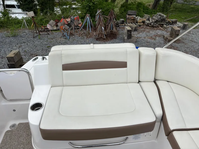 Slide: The Image of 2014 Chaparral 224 Sunesta boat seating with white and brown upholstery, cup holder visible. - 15