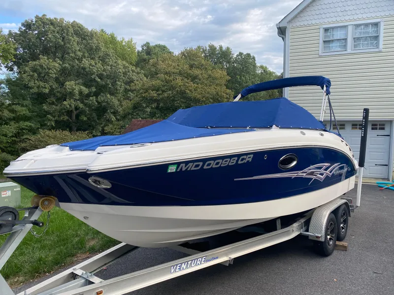 Slide: The Image of 2014 Chaparral 224 Sunesta boat on trailer, blue cover, parked near house. - 2