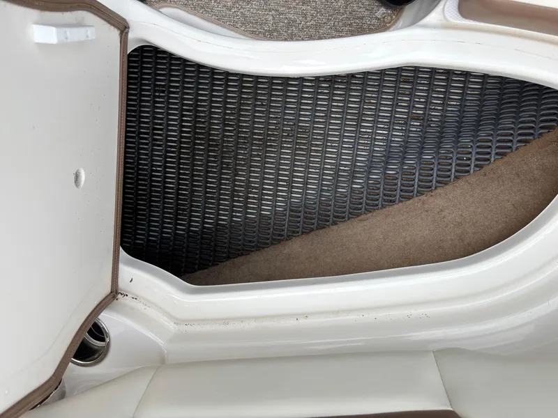 Slide: The Image of 2014 Chaparral 224 Sunesta storage compartment with textured mat and white interior. - 22
