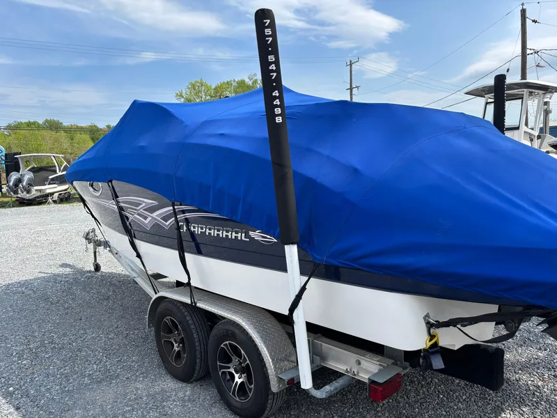Slide: The Image of 2014 Chaparral 224 Sunesta boat on trailer, covered with blue tarp, parked outdoors. - 3