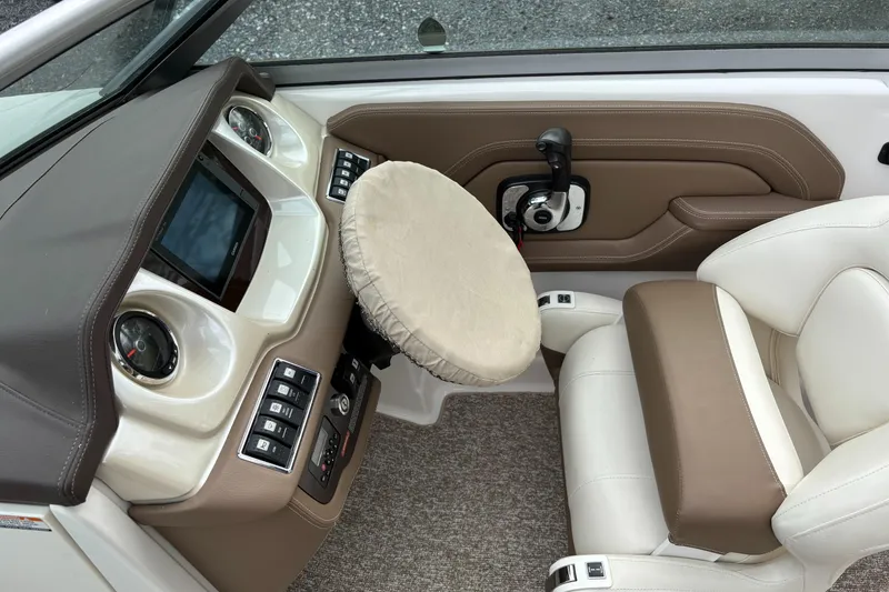 Slide: The Image of 2014 Chaparral 224 Sunesta boat interior with steering wheel cover and beige seating. - 30