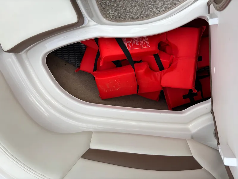 Slide: The Image of Storage compartment with red life jackets in a 2014 Chaparral 224 Sunesta boat. - 34