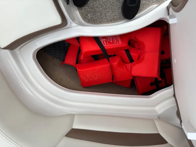 Slide: The Image of Storage compartment with red life jackets in a 2014 Chaparral 224 Sunesta boat. - 35