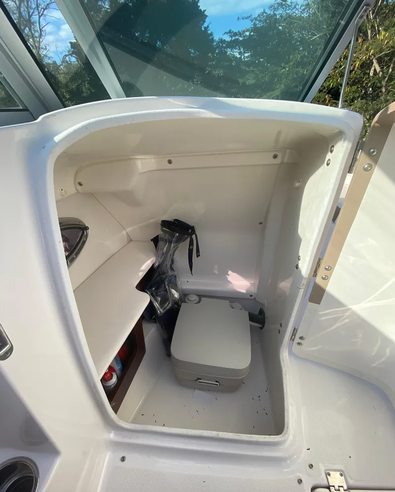 Slide: The Image of 2014 Chaparral 224 Sunesta boat interior with storage compartment and portable toilet. - 40