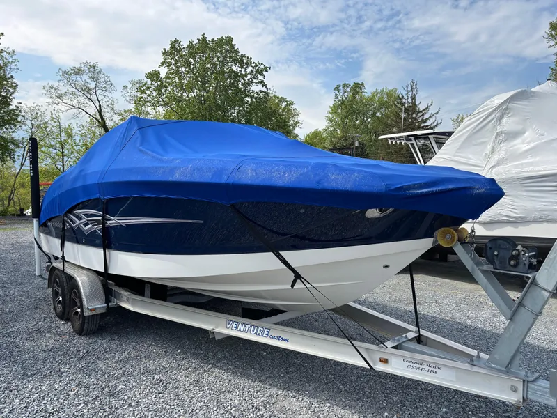 Slide: The Image of 2014 Chaparral 224 Sunesta boat on trailer, covered with blue tarp, parked outdoors. - 6