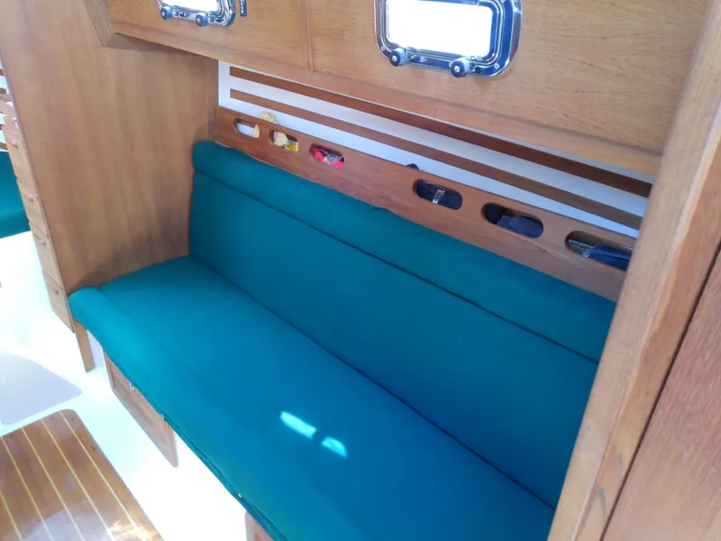 Slide: The Image of Interior of 2017 Com-Pac 27/3 sailboat with teal seating and wooden cabinetry. - 33