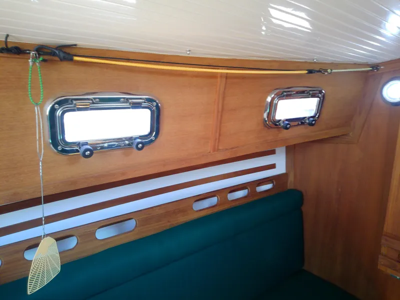 Slide: The Image of Interior of 2017 Com-Pac 27/3 sailboat with wooden finish and green seating. - 34