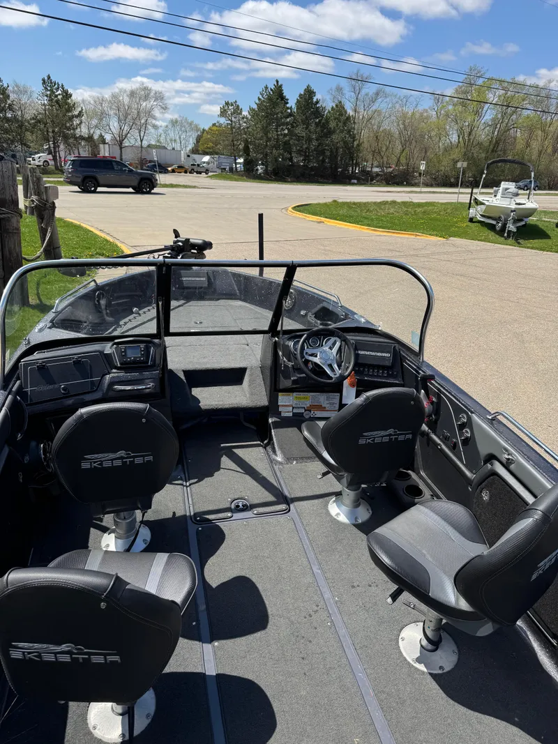 Slide: The Image of 2022 Skeeter Solera 205 boat interior with seating and steering wheel, parked outdoors. - 12