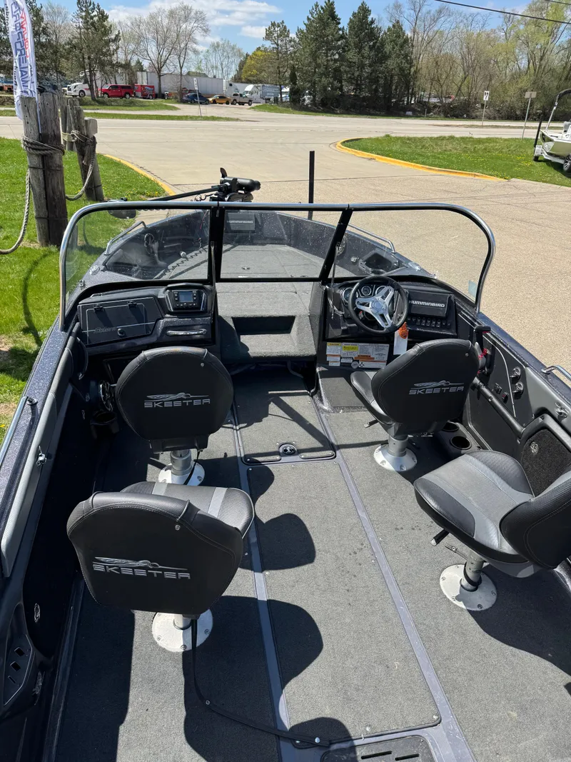 Slide: The Image of 2022 Skeeter Solera 205 boat interior with seating and steering console, parked outdoors. - 13