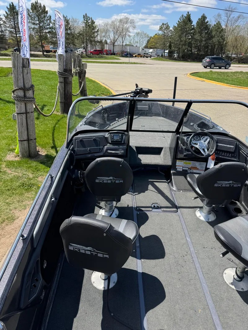 Slide: The Image of 2022 Skeeter Solera 205 boat interior with seating and steering wheel, parked outdoors. - 14