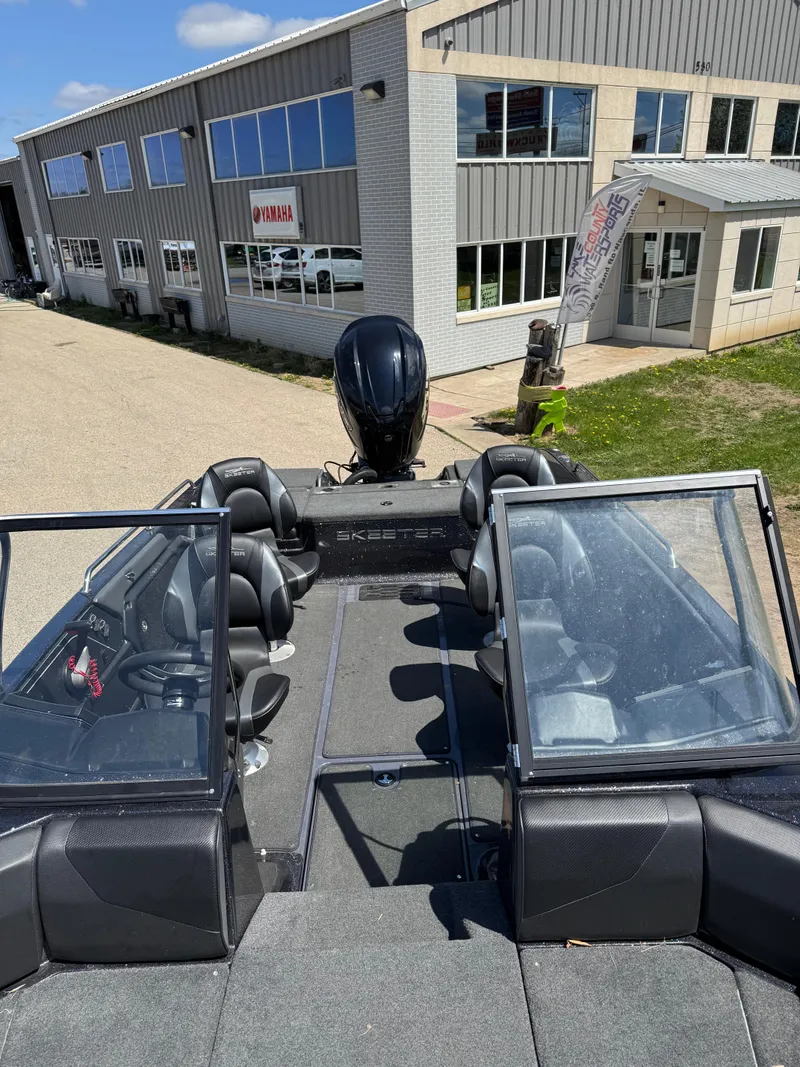 Slide: The Image of 2022 Skeeter Solera 205 boat with open cockpit, parked near a modern building. - 19