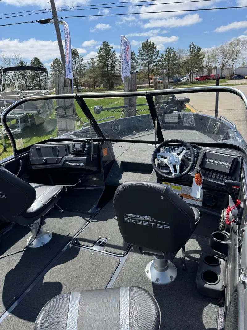 Slide: The Image of 2022 Skeeter Solera 205 boat interior with steering wheel and seating, parked outdoors. - 9