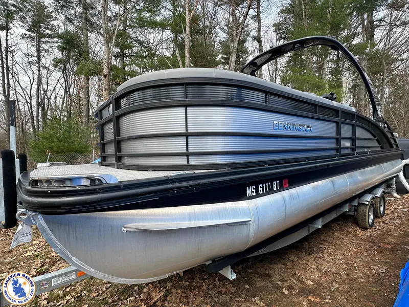 Slide: The Image of 2020 Bennington R 25 RSBA pontoon boat on a trailer in a wooded area. - 2
