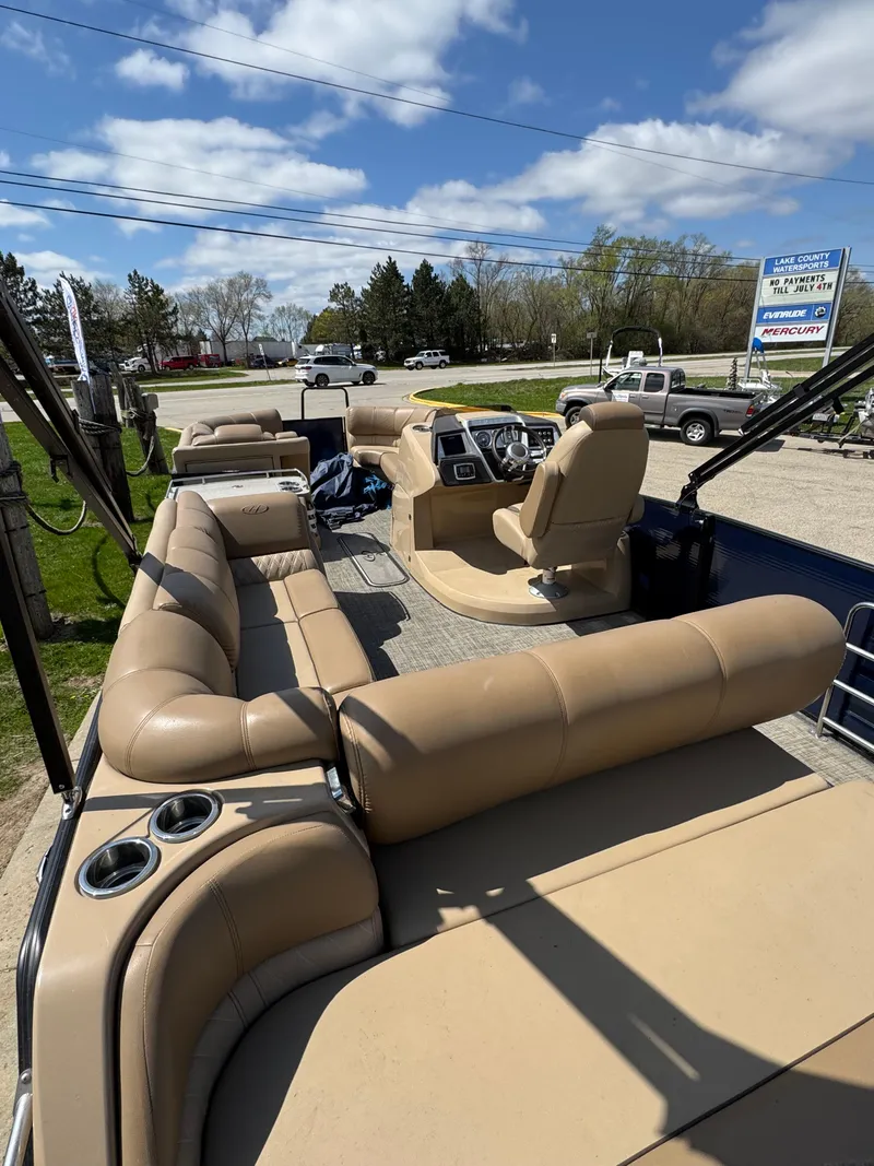 Slide: The Image of 2018 Harris Grand Mariner 230 pontoon boat with beige seating, parked outdoors under a blue sky. - 13