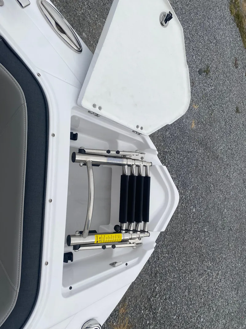 Slide: The Image of 2025 Monterey 258 Super Sport boat ladder compartment, open on a textured surface. - 28