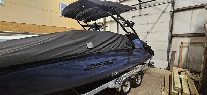 Slide: The Image of 2023 Yamaha Boats 255XD covered in a garage, showcasing sleek design and trailer. - 10