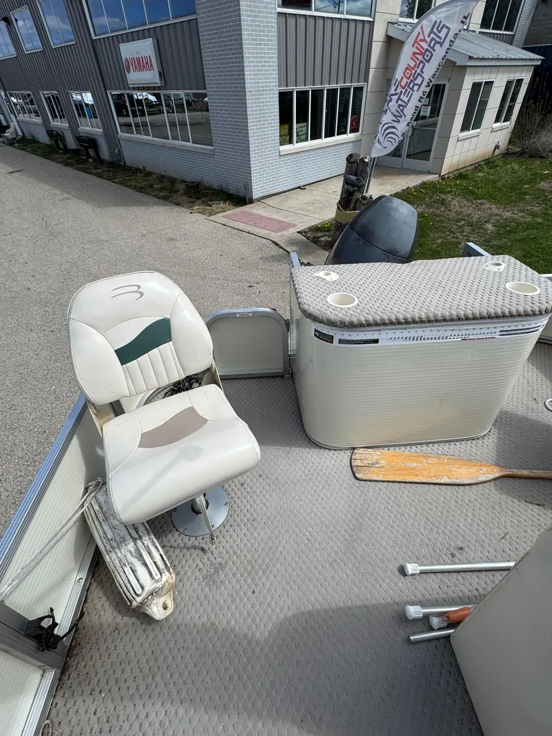 Slide: The Image of 2007 Bennington 2050 FSI boat interior with seating and console, parked near a building. - 11