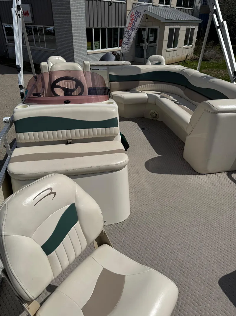 Slide: The Image of 2007 Bennington 2050 FSI pontoon boat with beige and green seating, docked near a building. - 24