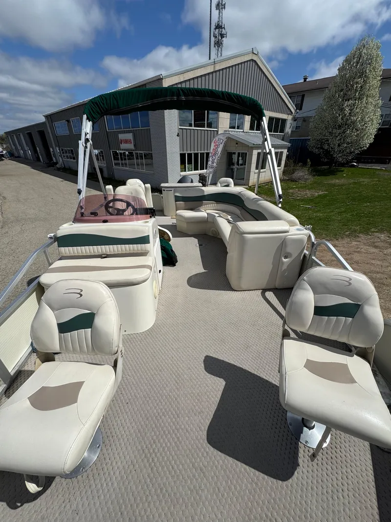 Slide: The Image of 2007 Bennington 2050 FSI pontoon boat with spacious seating, docked near a building. - 25