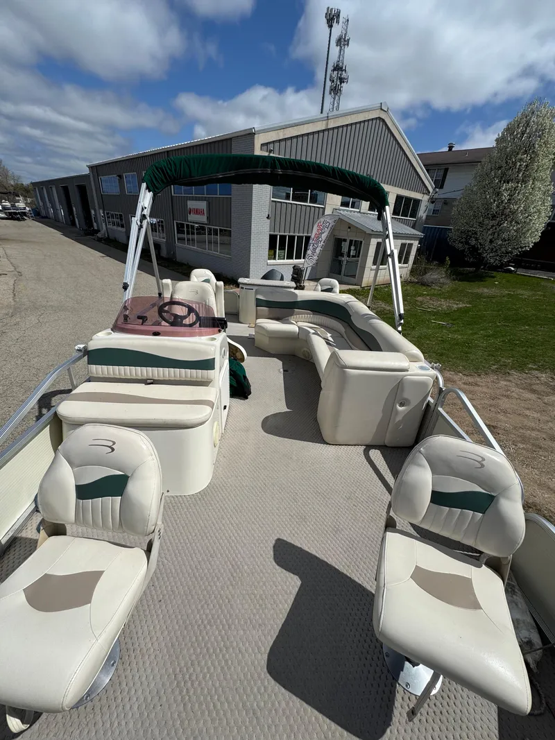 Slide: The Image of 2007 Bennington 2050 FSI pontoon boat with seating, parked outdoors under a cloudy sky. - 26