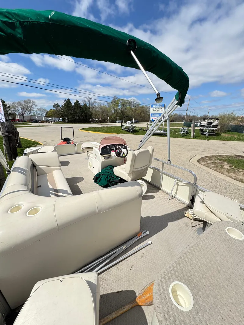 Slide: The Image of 2007 Bennington 2050 FSI pontoon boat with green canopy, beige seating, and open deck. - 29