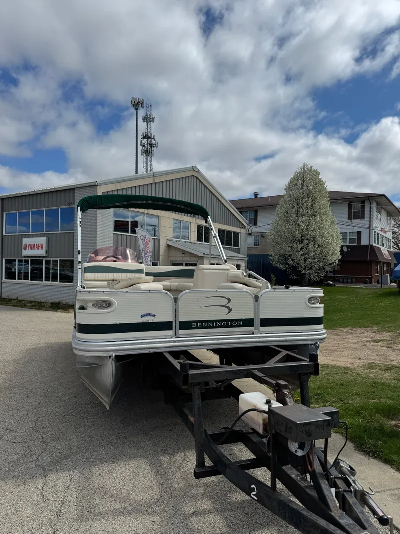 Slide: The Image of 2007 Bennington 2050 FSI pontoon boat on trailer, parked near buildings under cloudy sky. - 4