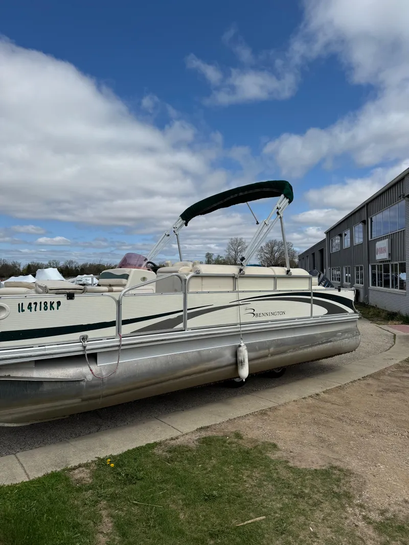 Slide: The Image of 2007 Bennington 2050 FSI pontoon boat parked outdoors near a building under a cloudy sky. - 5