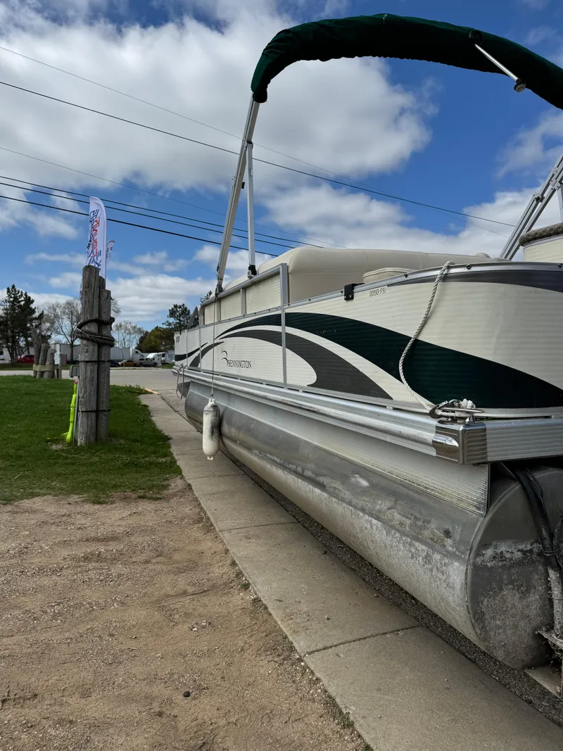 Slide: The Image of 2007 Bennington 2050 FSI pontoon boat parked on a concrete path under a cloudy sky. - 9