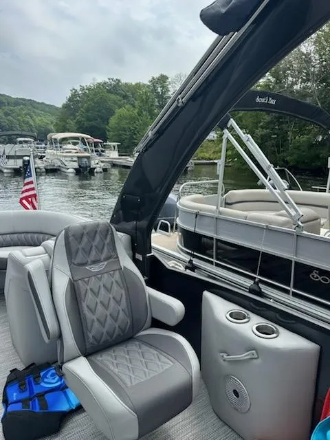 Slide: The Image of 2022 Bennington QX 23 Quad Bench boat interior with luxurious seating, docked near other boats. - 10